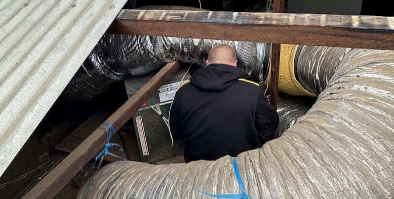 Licensed air conditioning installer working on a ducted system in the roof. 